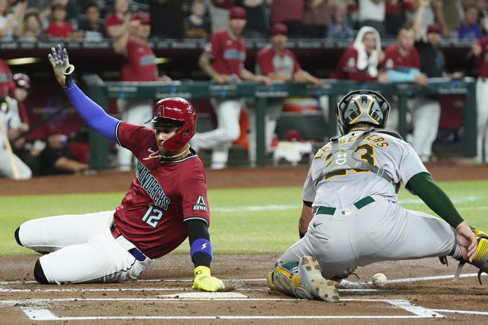 Arizona Diamondbacks' Lourdes Gurriel Jr. (12) appears to score a run as Oakland Athletics catcher Shea Langeliers, right, is unable to make a catch during the first inning of a baseball game Saturday, June 29, 2024, in Phoenix. Gurriel was sent back to third base on an umpire replay on a double hit by Diamondbacks' Christian Walker. (AP Photo/Ross D. Franklin)
