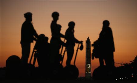 Tourists on Segways are briefed on history and current events, namely the potential government shutdown, during a stop near the U.S. Capitol as the sun sets behind the Washington Monument (C, background) in Washington September 30, 2013. REUTERS/Kevin Lamarque