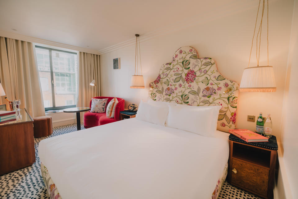 A bed with white linens and a fabric headboard at The Leinster Hotel in Dublin, Ireland