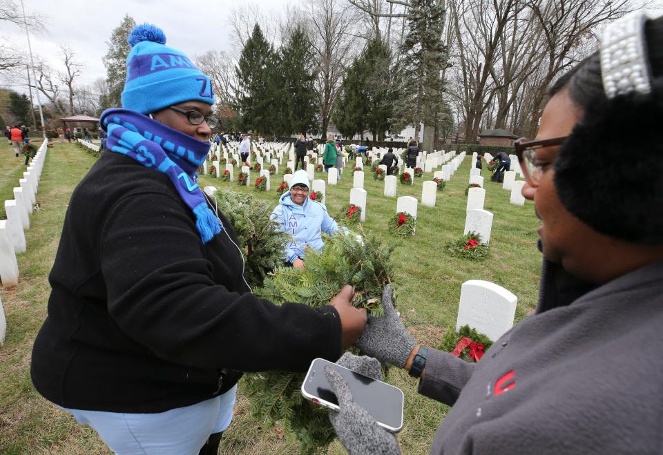 Amicae Branch, Danielle Crawford and Onicka Williams placed wreaths at gravesites.  About a thousand volunteers teamed up to place 6000 wreaths at the graves of soldiers buried at Zachary Taylor National Cemetery on Saturday, December 17, 2022