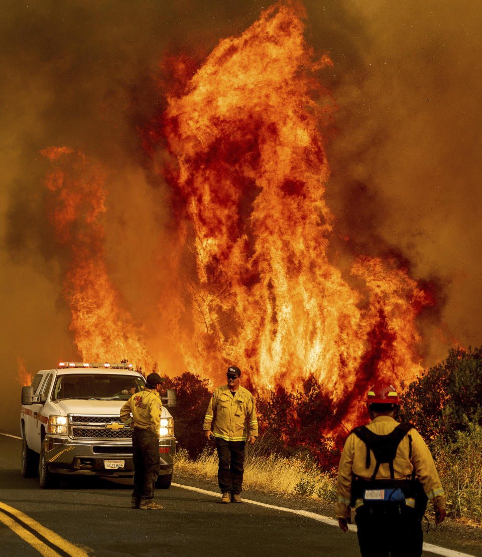 Flames from the LNU Lightning Complex fires leap above Butts Canyon Road on Sunday, Aug. 23, 2020, as firefighters work to contain the blaze in unincorporated Lake County, Calif. (AP Photo/Noah Berger)