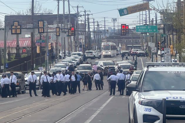 Police and officials gather on a cordoned off street at the scene of the shooting.