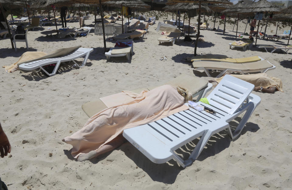 FILE - In this Friday, June 26, 2015 file photo, covered bodies lie on a beach in Sousse, Tunisia. More than 30 people have been summoned to face trial over the Tunisia's deadliest attack in a Mediterranean resort. The trial is scheduled to reopen on Tuesday Jan.29, 2019 in Tunis, more than 3-1/2 years after the attack on the Imperial Hotel in the beach resort of Sousse left 38 people dead, mostly British tourists. (Jawhara FM via AP, File)