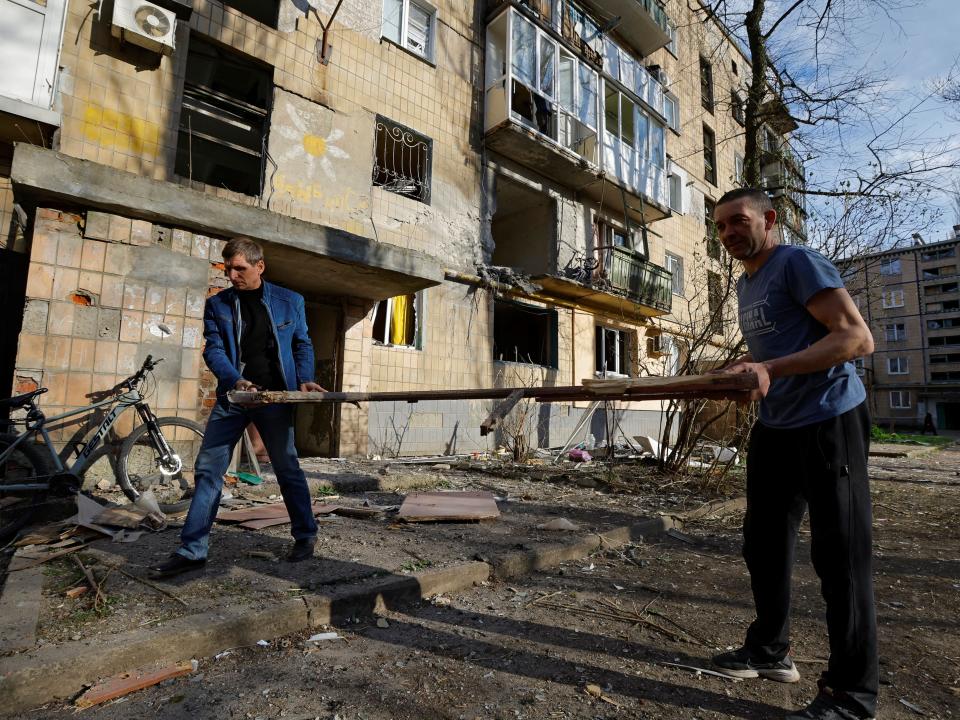 Local residents remove debris outside an apartment building hit by shelling (REUTERS)