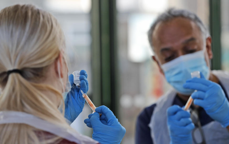 Doctor Anil Mehta and Apprentice Nursing Associate Ellie Bull prepare syringes with doses of the AstraZeneca vaccine at the Welcome Centre in Ilford, east London, Friday, Feb. 5, 2021. Mehta and his small team of doctors and nurses have been pitching up at homeless centers in his local area, a COVID-19 hotspot, offering a free jab to dozens who may otherwise get left behind in Britain's mass vaccination drive. (AP Photo/Frank Augstein)