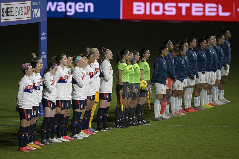 Players from the United States, left, and Argentina teams stand during the national anthems before a SheBelieves Cup women's soccer match, Wednesday, Feb. 24, 2021, in Orlando, Fla. (AP Photo/Phelan M. Ebenhack)