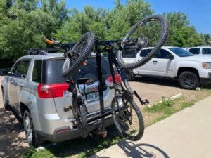Chuck Rack bike carry system holding two mountain bikes mounted to the back of a silver mini van in a parking lot