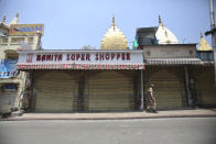 An Indian paramilitary soldier stands near closed shops in Jammu, India, Sunday, June 7, 2020. India whose coronavirus caseload is fifth highest in the world has partially restored trains and domestic flights and allowed reopening of shops and manufacturing. (AP Photo/Channi Anand)