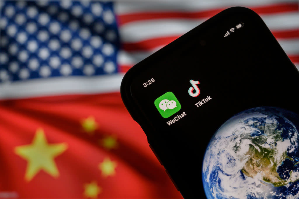 In this photo illustration, a cellphone can be seen displaying the logos for Chinese apps WeChat and TikTok in front of a monitor showing the flags of the United States and China.