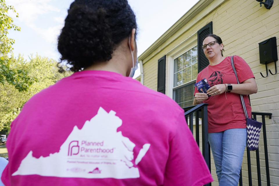 In this Saturday, Oct. 16, 2021, photo Han Jones of Planned Parenthood Advocates of Virginia , left, talks with Democratic voter, Danielle Clark while canvassing the area to encourage voters to vote in Richmond, Va. (AP Photo/Steve Helber)