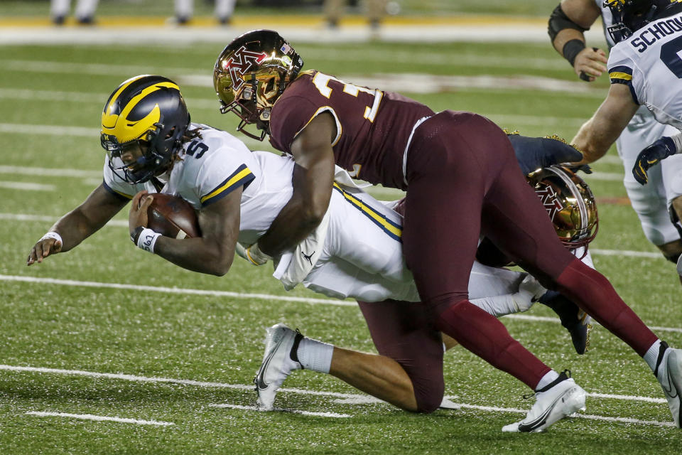 Michigan quarterback Joe Milton (5) leaps forward as Minnesota defensive lineman Boye Mafe (34) tackles him in the second quarter of an NCAA college football game Saturday, Oct. 24, 2020, in Minneapolis. (AP Photo/Bruce Kluckhohn)