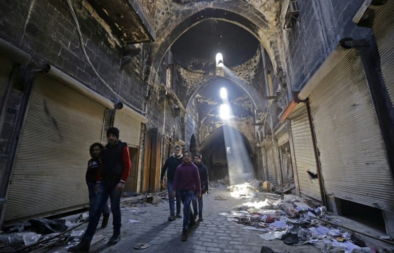 Syrian children walk down a damaged street in the old city of Aleppo on January 22, a month after pro-regime forces retook the city from rebel fighters