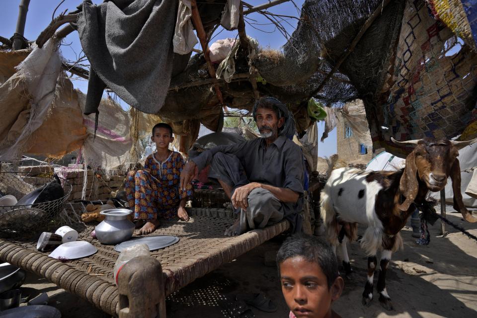 Kalu Khan, who lost his wife in a 2022 flood, sits with his children inside their tent set up over the rubble of their damaged home caused by the floods, at a village in Dada, a district of Pakistan's Sindh province, Wednesday, May 17, 2023. A year on from the floods in Pakistan that killed at least 1,700 people, destroyed millions of homes, wiped out swathes of farmland, and caused billions of dollars in economic losses, the country still hasn't fully recovered. (AP Photo/Anjum Naveed)