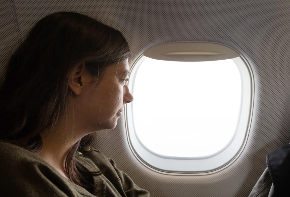 Young caucasian woman flying by plane, high in the sky