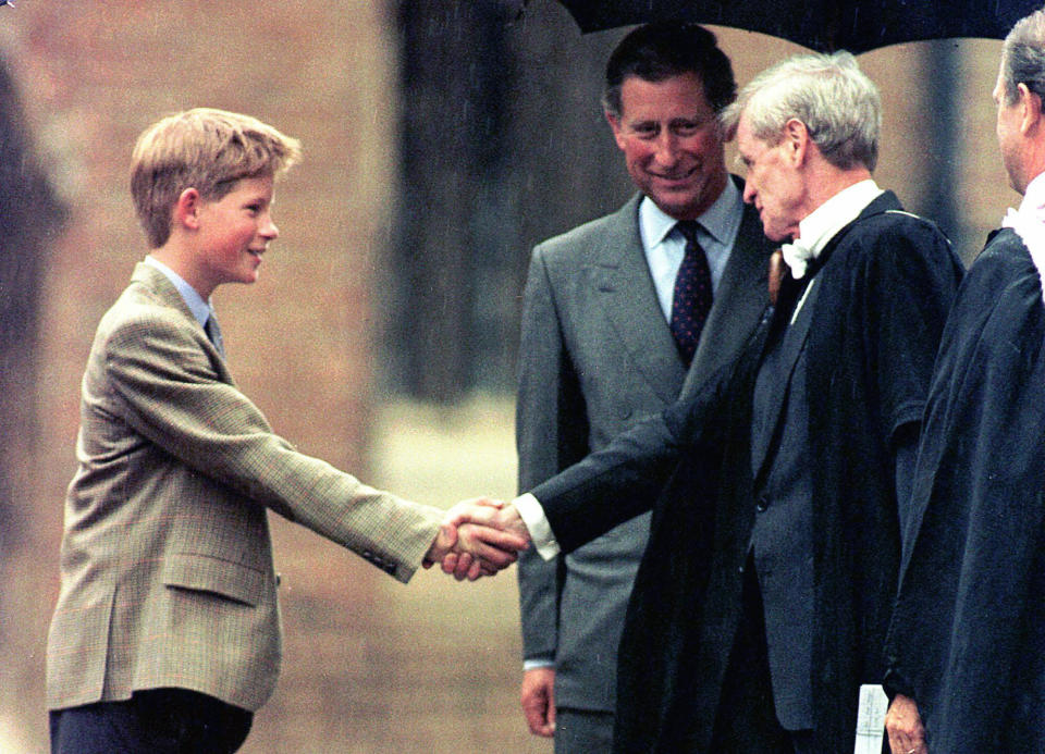 FILE - In this Wednesday, Sept. 2, 1998 file photo, Britain's Prince Harry meets Headmaster John Lewis, right, as Prince Charles looks on, after his arrival at the prestigious Eton college, in Eton, England. Princess Diana’s little boy, the devil-may-care red-haired prince with the charming smile is about to become a father. The arrival of the first child for Prince Harry and his wife Meghan will complete the transformation of Harry from troubled teen to family man, from source of concern to source of national pride. (Pool Photo via AP, File)