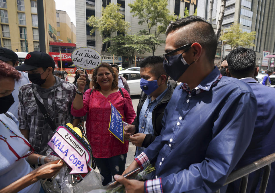 A relative of a same sex couple holds up a banner that reads in Spanish " The wedding of the year" during a mass wedding ceremony organized by city authorities as part of the LGBT pride month celebrations, in Mexico City, Friday, June 24, 2022. (AP Photo/Fernando Llano)