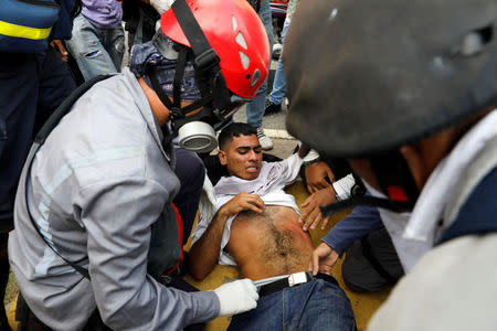 An opposition supporter is helped during a clash with security forces in a rally against Venezuela's President Nicolas Maduro in Caracas, Venezuela, April 26, 2017. REUTERS/Carlos Garcia Rawlins