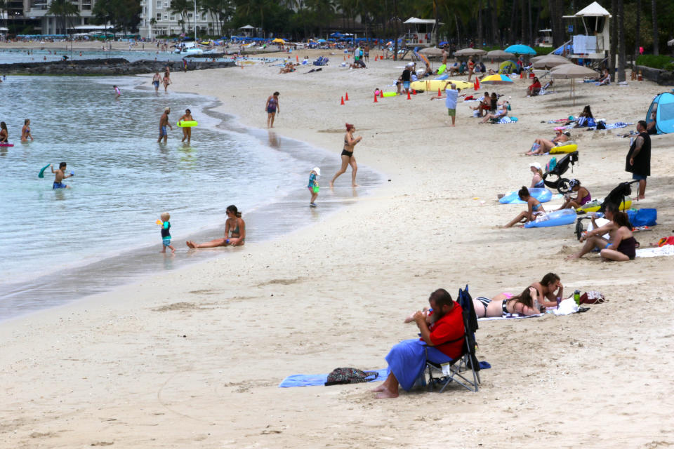 FILE — In this Aug. 24, 2021, file photo people sit on a Waikiki Beach in Honolulu. Hawaii officials are facing pressure to increase COVID-19 testing for travelers. The islands are weathering a record surge and federal guidelines are being changed to require negative virus tests from both vaccinated and unvaccinated travelers to the U.S. State leaders have resisted implementation of a two-test policy for arriving travelers despite evidence that more COVID-19 testing would help reduce the spread of disease, especially in an isolated destination location like Hawaii. (AP Photo/Caleb Jones, File)