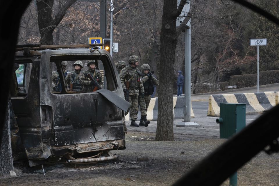 FILE - Soldiers are seen though a bus, which was burned during clashes, as they patrol a street near the central square blocked by Kazakhstan troops and police in Almaty, Kazakhstan, Monday, Jan. 10, 2022. On Jan. 2, small protests broke out in an oil city in western Kazakhstan where residents were unhappy about a sudden spike in prices for liquified gas, which is widely used as automotive fuel. By Jan. 5, the protests descended into violence, with armed groups storming government buildings and setting cars and buses on fire in Kazakhstan's largest city, Almaty. (AP Photo/Vasily Krestyaninov, File)