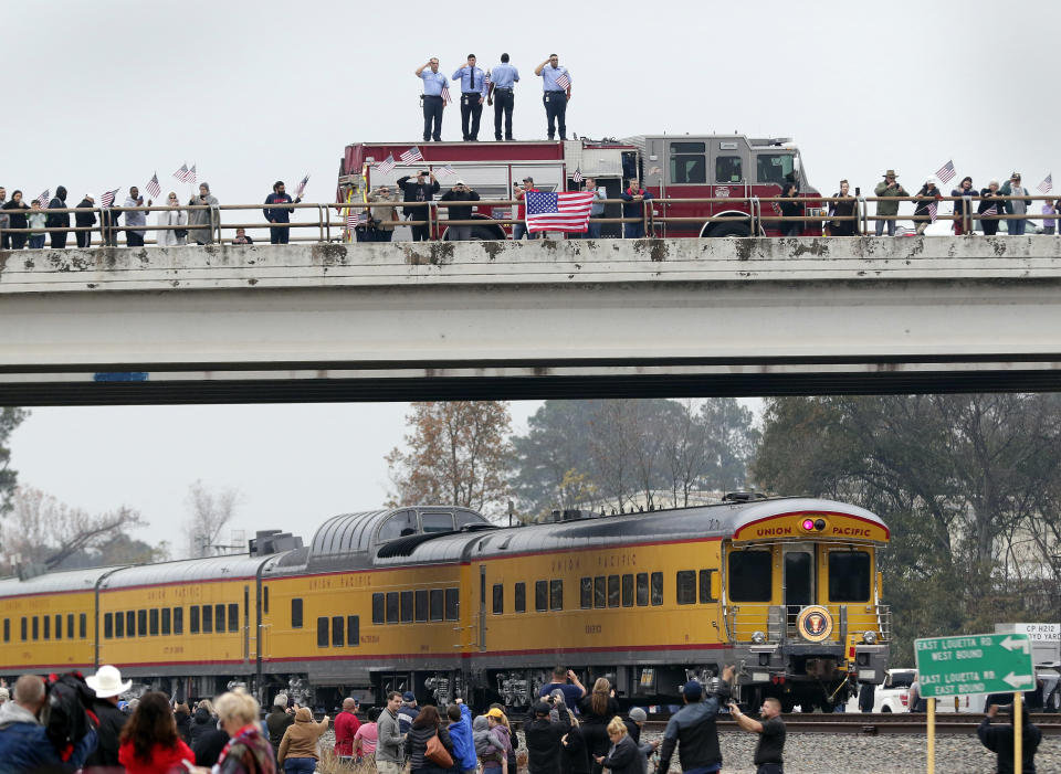 Firefighters stand on their truck and salute along with other attendants on an overpass as the train carrying the body of former president George H.W. Bush travels past on the way to Bush’s final internment Thursday, Dec. 6, 2018, in Spring, Texas. (Photo: Michael Wyke/AP)