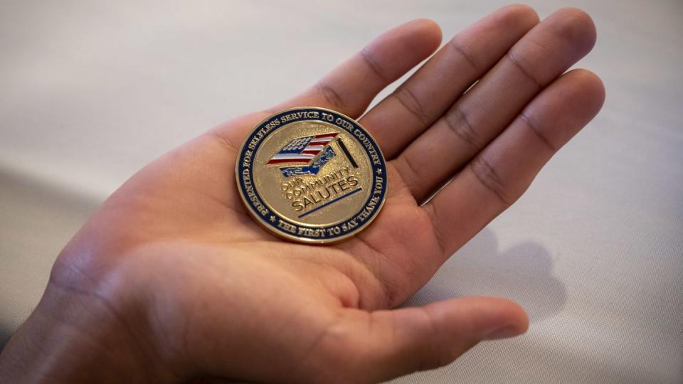 An Abington Senior High School graduate, future sailor Demitrius Rodrigues, with Navy Talent Acquisition Group Philadelphia, displays a challenge coin presented during a Montgomery County Our Community Salutes ceremony in Lansdale, Pennsylvania. (Mass Communication Specialist 1st Class Diana Quinlan/Navy)