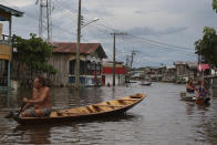 Residents navigate flooded streets in Anama, Amazonas state, Brazil, Thursday, May 13, 2021. (AP Photo/Edmar Barros)