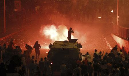 A riot police officer, on a armoured personnel carrier surrounded by anti-Mursi protesters (foreground), fires rubber bullets at members of the Muslim Brotherhood and supporters of ousted Egyptian President Mohamed Mursi along a road at Ramsis square, which leads to Tahrir Square, during clashes at a celebration marking Egypt's 1973 war with Israel, in Cairo in this October 6, 2013 file photo. REUTERS/Amr Abdallah Dalsh/Files