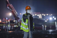 In this Tuesday, Jan. 28, 2020 photo, a construction worker rests at the site of the Huoshenshan temporary field hospital being built in Wuhan in central China's Hubei Province. China as of Wednesday has more infections of a new virus than it did in with SARS, though the death toll is still lower. (Chinatopix via AP)