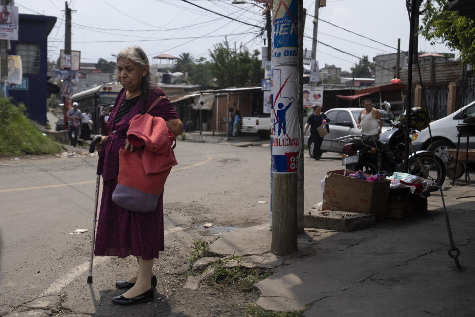 An elderly woman waits to cross a street at the Mario Alioto neighborhood in Villanueva, Guatemala, Tuesday, May 16, 2023. One of the most populated slums in Guatemala with approximately 70 thousand neighbors, the Mario Alioto neighborhood is disputed between rival criminal gangs. (AP Photo/Moises Castillo)