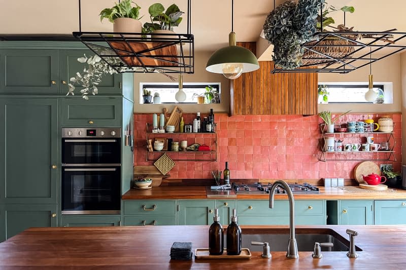 Reddish pink tile backsplash with green cabinets in newly renovated kitchen