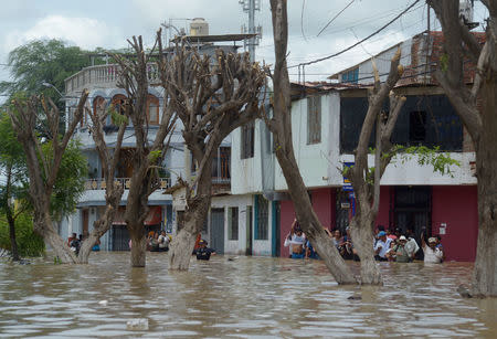 Residents cross a flooded street after rivers breached their banks due to torrential rains, causing flooding and widespread destruction in Piura, Peru, March 27, 2017. REUTERS/Miguel Arreategui