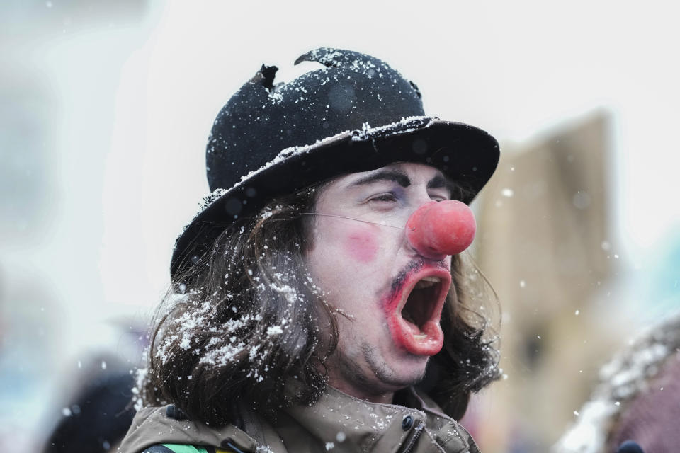 A man made up as a clown attends a demonstration against the annual meeting of the World Economic Forum in Davos, Switzerland, Sunday, Jan. 15, 2023. The annual meeting of the World Economic Forum is taking place in Davos from Jan. 16 until Jan. 20, 2023. (AP Photo/Markus Schreiber)