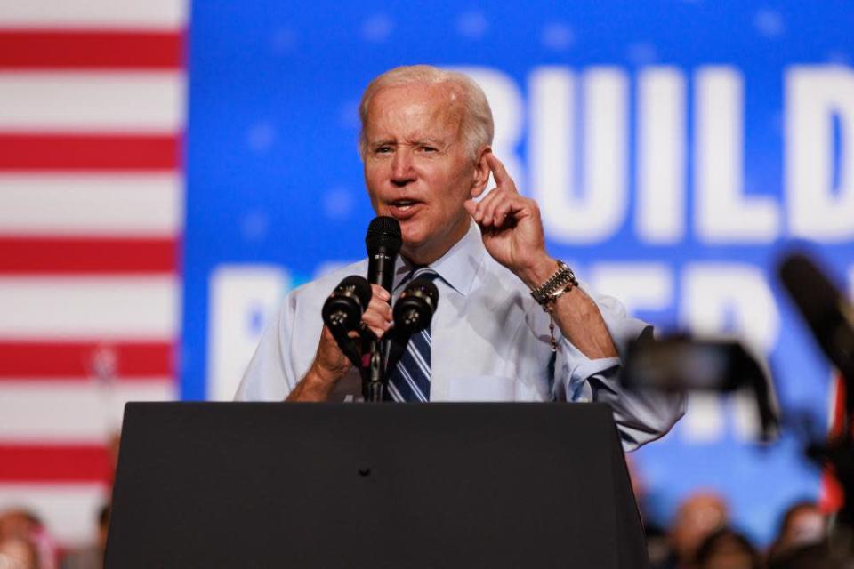 Joe Biden steht auf einem Podium vor dem Hintergrund eines rot-weiß-blauen „Building A Better America“-Schildes.