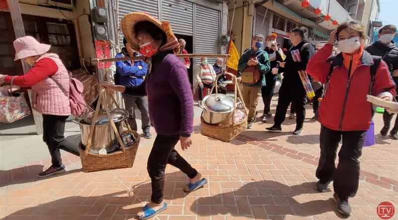 高齡76歲的阿嬤挑著傳統扁擔，裝著兩大鍋熱食，來回在街上穿梭。(圖／翻攝自白沙屯媽祖網路電視台)
