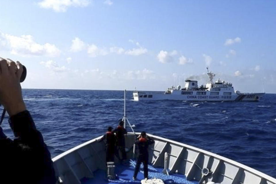 In this photo provided by the Philippine Coast Guard, a Chinese coast guard ship, top, tries to block a Philippine government vessel at the disputed South China Sea on Thursday March 21, 2024. Chinese coast guard ships, backed by a military helicopter, tried to dangerously block but failed to stop two Philippine government vessels carrying scientists from reaching two barren sandbars called Sandy Cay in the disputed South China Sea, Philippine officials said Friday. (Philippine Coast Guard via AP)