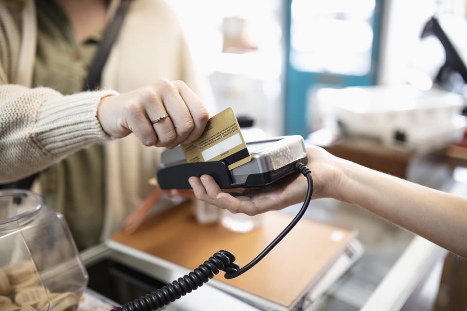 Close up female shopper paying, using credit card reader in shop