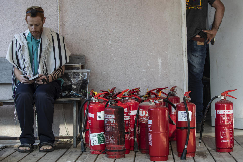 A Jewish student prays in the synagogue of the Maoz Military Preparation Program after it was damaged by fire during overnight clashes in the mixed Jewish-Arab city of Lod, Israel, Friday, May 14, 2021. (AP Photo/Heidi Levine)