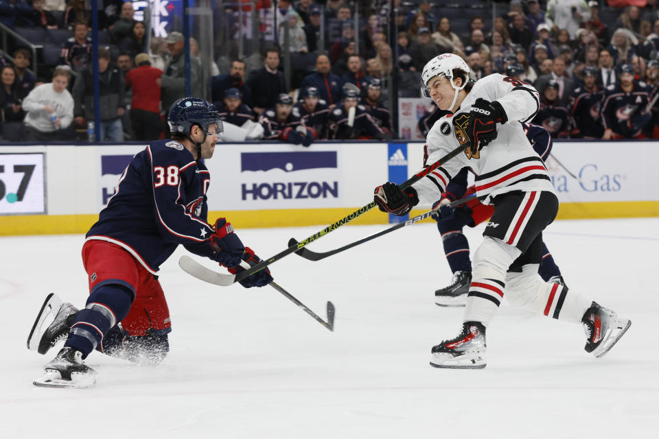 Chicago Blackhawks' Connor Bedard, right, tries to shoot the puck past Columbus Blue Jackets' Boone Jenner during the first period of an NHL hockey game Wednesday, Nov. 22, 2023, in Columbus, Ohio. (AP Photo/Jay LaPrete)