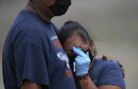 A couple wearing masks and gloves to protect themselves from the new coronavirus mourn during the burial of their loved one at the newly constructed Valle de Chalco Municipal Cemetery, built to accommodate the rise in deaths amid the new coronavirus pandemic, on the outskirts of Mexico City, Thursday, May 21, 2020. (AP Photo/Marco Ugarte)