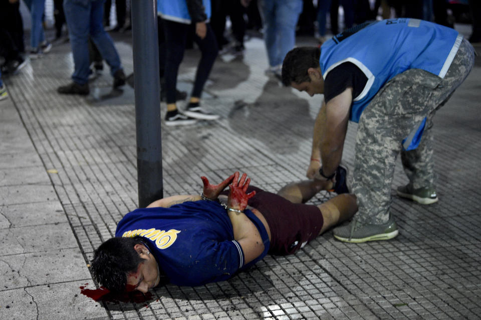 Un hincha de Boca Juniors, esposado y ensangrentado, yace de bruces luego que la policía dispersó a la multitud que se congregó en el icónico Obelisco de Buenos Aires, pese a la derrota del equipo por 2-1 ante Fluminense, el 4 de noviembre de 2023 (AP Foto/Gustavo Garello).