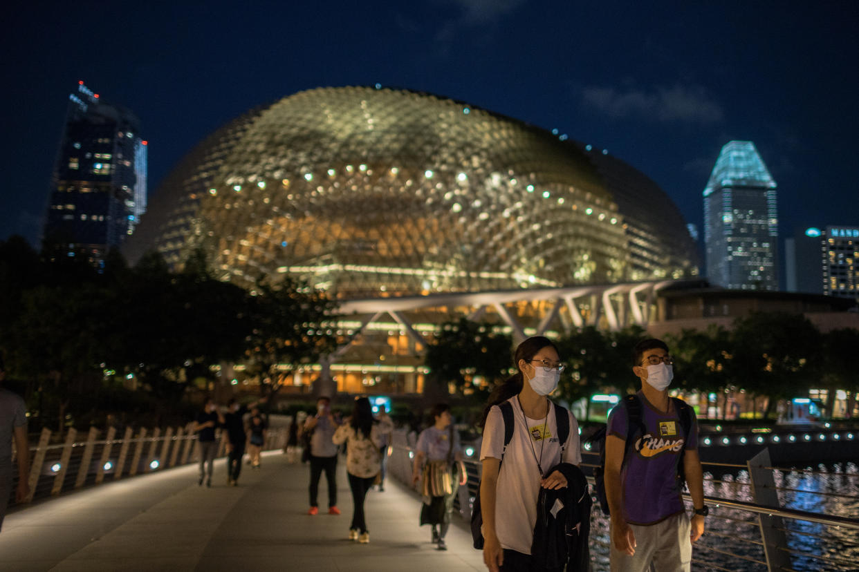 People wearing protective surgical masks walk towards the Merlion Park in Singapore on 12 February, 2020. (PHOTO: LightRocket via Getty Images)