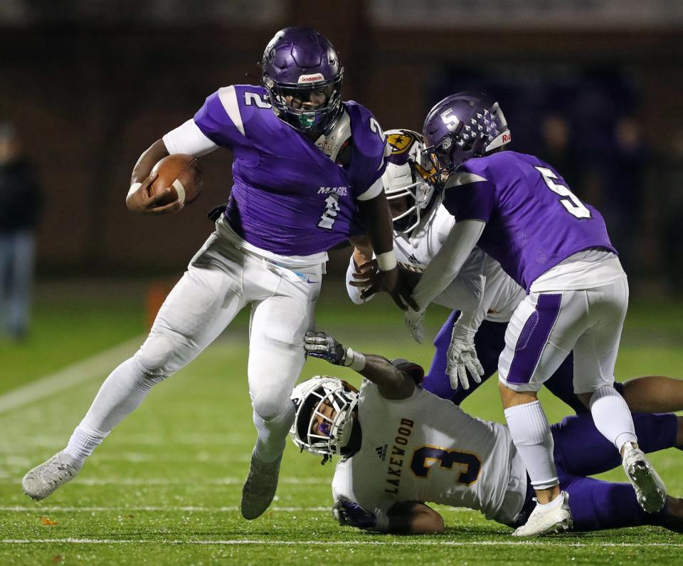 Barberton running back Cameron Macon breaks away from a pair of Lakewood defenders during the first half of a Division II playoff football game, Friday, Oct. 29, 2021, in Barberton, Ohio.