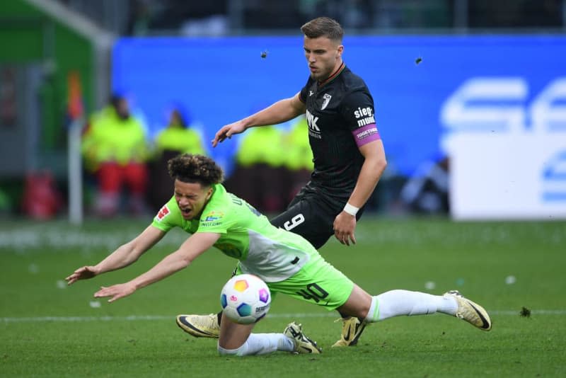 Augsburg's Ermedin Demirovic (R) and Wolfsburg's Kevin Paredes battle for the ball during the German Bundesliga soccer match between VfL Wolfsburg and FC Augsburg Volkswagen Arena. Swen Pförtner/dpa