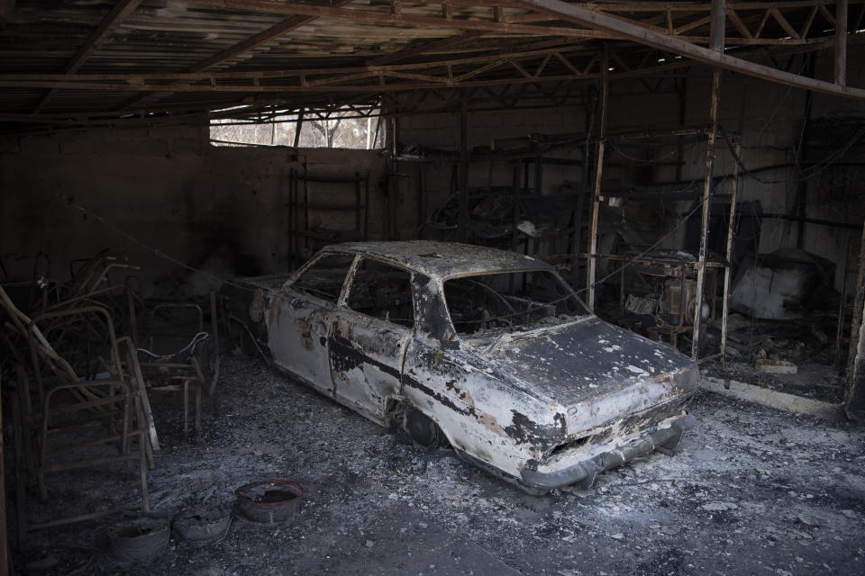 The view of a burned car after a wildfire in the Fyli suburb, northwest Athens, Greece, Friday, Aug. 25, 2023. Authorities battling a major wildfire in northeastern Greece that has been described as the European Union's largest single fire recorded have recovered another body, the fire department says, bringing the total death toll of wildfires in Greece this week to 21. (AP Photo/Michael Varaklas)