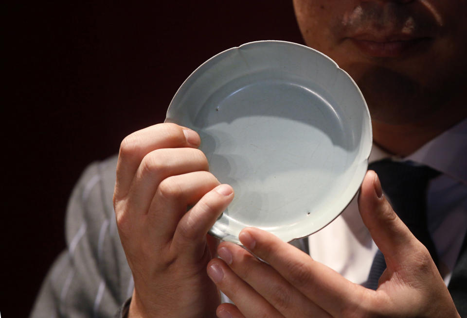 Nicolas Chow, Sotheby’s Asia Deputy Chairman, holds the Chinese Song Dynasty ceramics Ruyao Washer at the Sotheby's auction in Hong Kong Wednesday, April 4, 2012. The 900-year-old dish smashed the world record for Chinese Song Dynasty ceramics sold at auction, fetching US$26.7 million. (AP Photo/Kin Cheung)