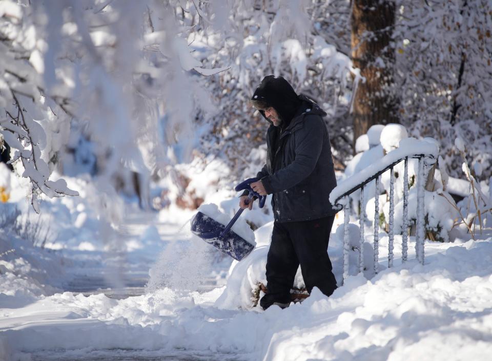 A man clears a walkway after a winter storm swept over the intermountain West and dropped up to eight inches of snow, Thursday, Dec. 29, 2022, in Denver.