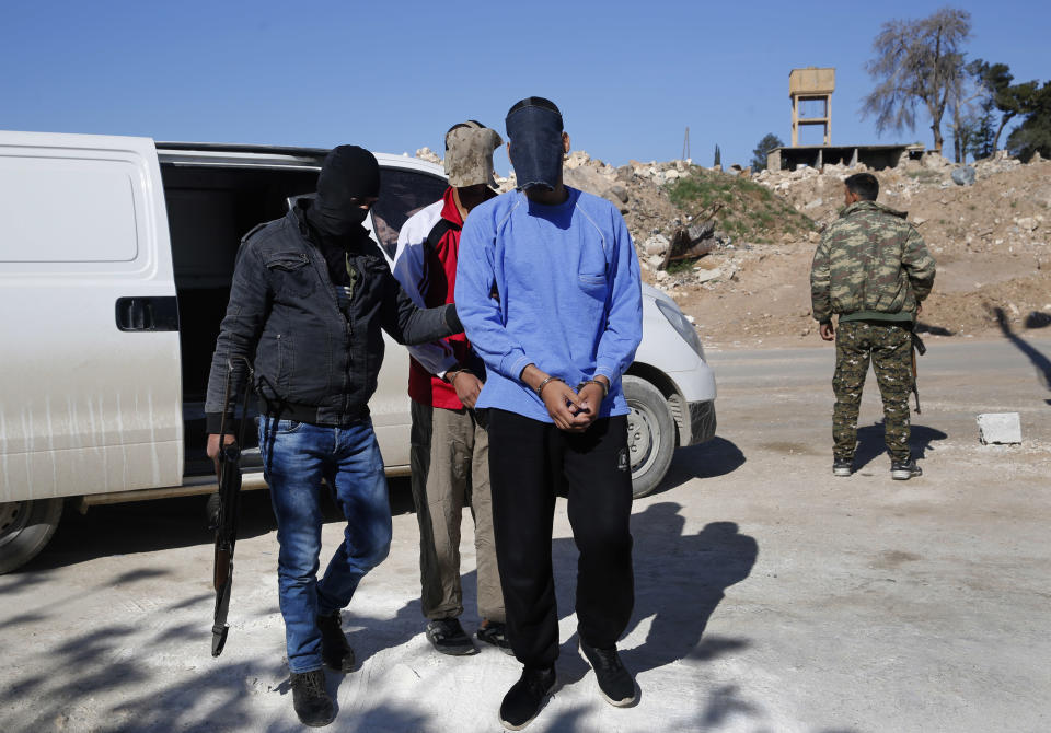 Kurdish security escorts two blindfolded British alleged members of an Islamic State group cell dubbed "The Beatles," known for beheading hostages, Alexanda Amon Kotey, foreground, and El Shafee Elsheikh, background, at a security center, in Kobani, Syria, Friday, March 30, 2018. (AP Photo/Hussein Malla)