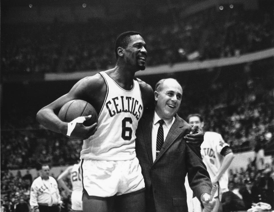 Bill Russell is congratulated by Boston Celtics coach Arnold "Red" Auerbach after scoring his 10,000th point in the NBA on Dec. 12, 1964, in Boston. The NBA great died on July 31, 2022.