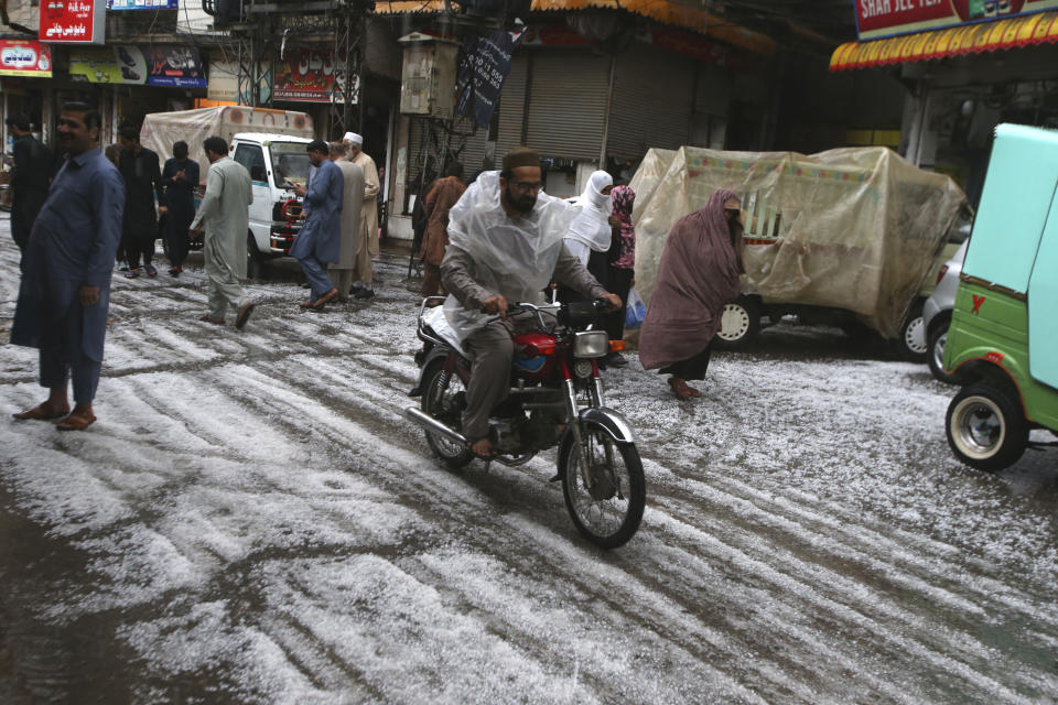 People walk on the road covered by hailstones due to heavy hailstones rain in Peshawar, Pakistan, Saturday, March 30, 2024. Heavy rains killed eight people, mostly children, and injured 12 in Pakistan's northwest, an official said Saturday. (AP Photo/Mohammad Sajjad)