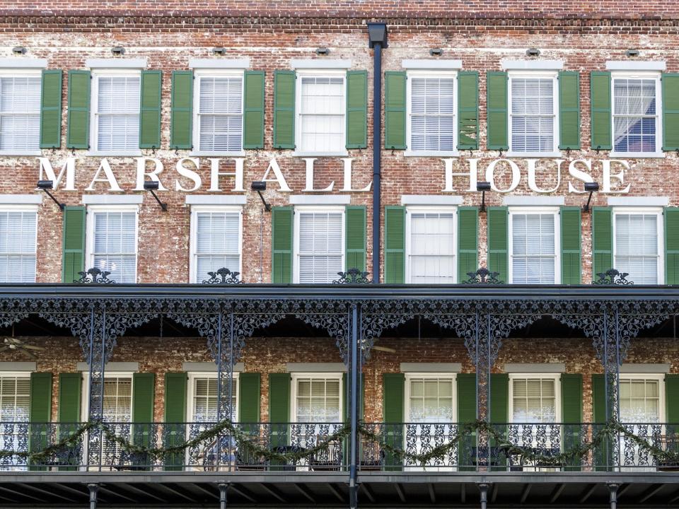 The outside of Marshall House in Savannah, Georgia, has green shutters and weathered brick.